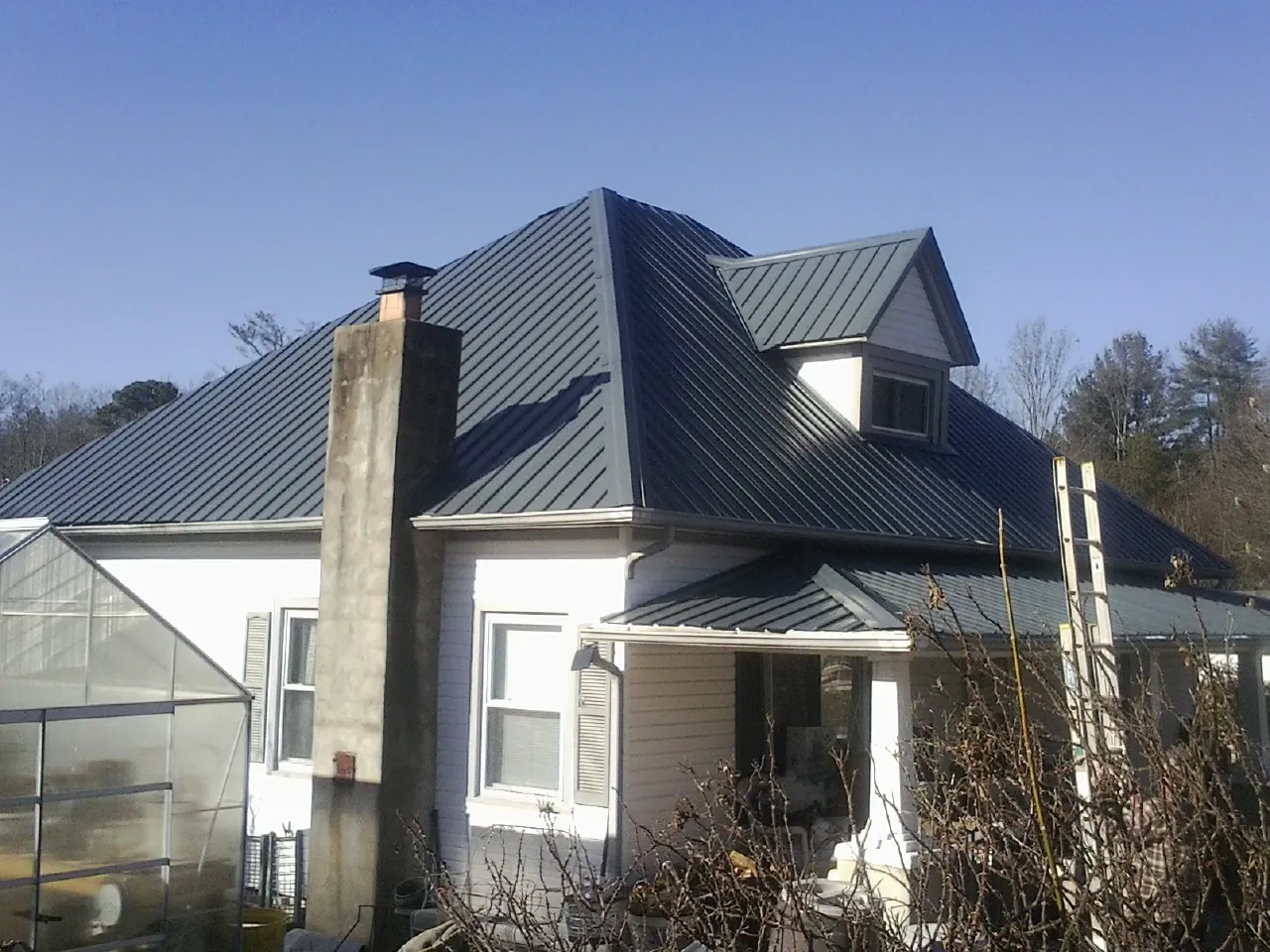 Dark blue standing seam metal roof on a white farmhouse with dormer — Slate & Tile Roof Repair by Roofing Brothers in Fort Ransom