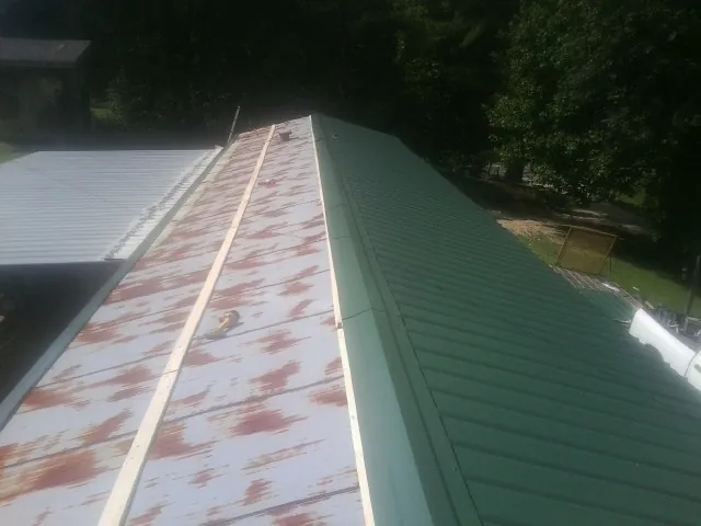 Old rusted panels beside newly installed green metal roofing — Wind Damage Roof Repair by Roofing Brothers in Fort Ransom