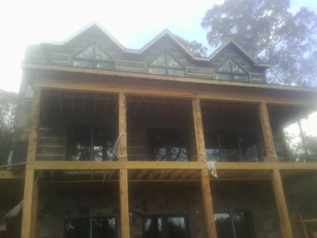 Dormers and porch framing on a large log home under construction — Roof Coating work by our crew in Fort Ransom