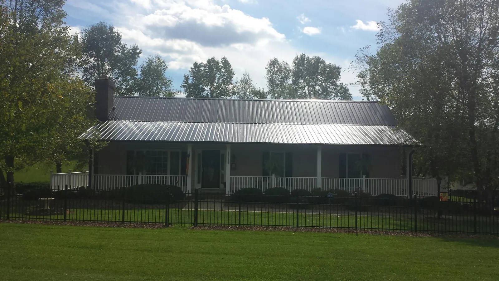 Gray metal roof on a brick ranch with a full width front porch — Gutter Guard Installation work by our crew in Fort Ransom