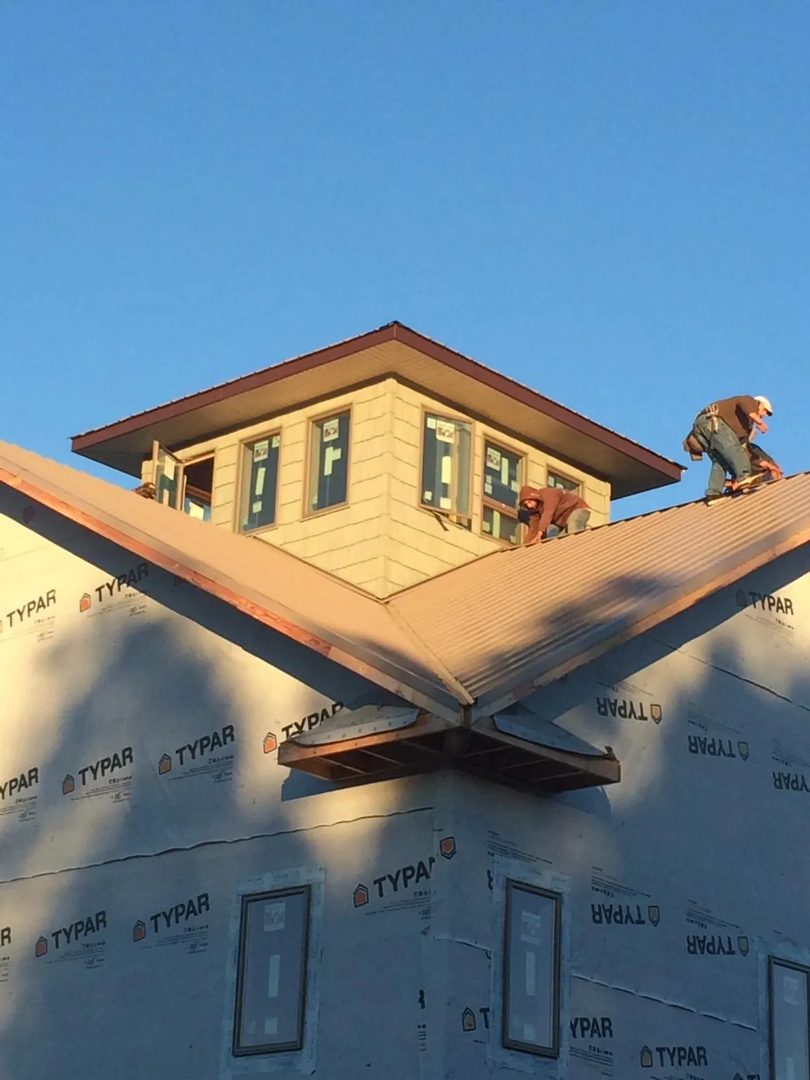 Roofers working around a rooftop cupola on a new metal roof at sunset — Roof Waterproofing in Fort Ransom by Roofing Brothers